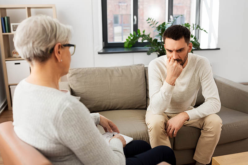 Senior woman psychologist and sad man patient